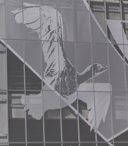 Perforated metal facade with abstract geometric pattern across building exterior