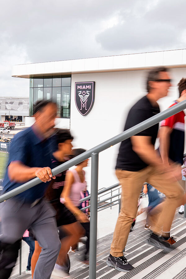 Fans walking up stadium steps toward entrance with Miami team logo visible on building
