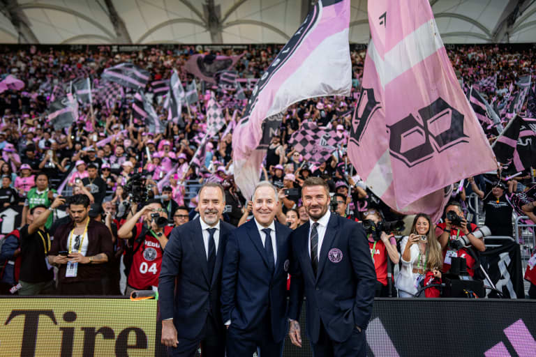 Inter Miami executives posing with fans and flags in crowded stadium