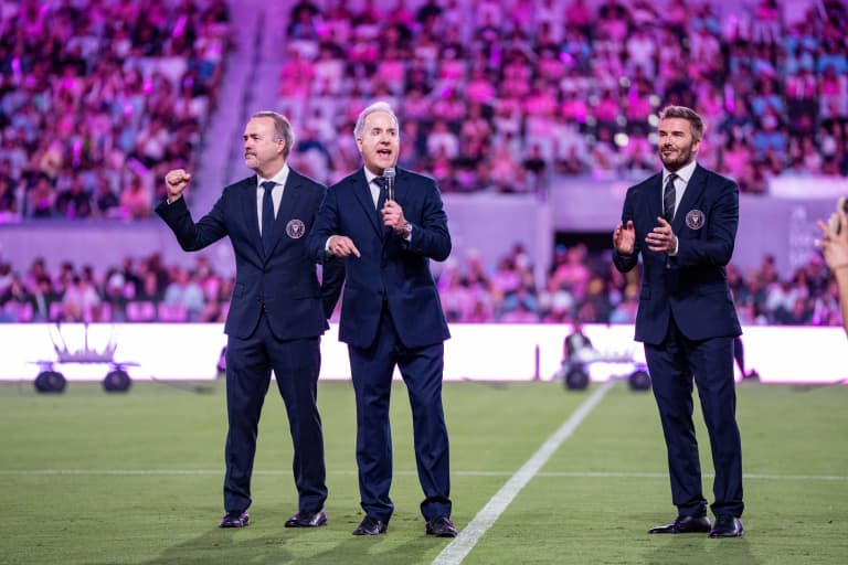 Three Inter Miami executives standing on field addressing crowd during event
