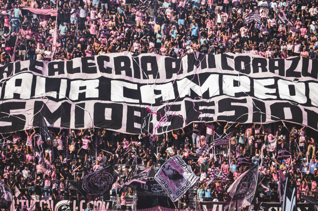 Inter Miami supporters hold a large banner in a crowded stadium section