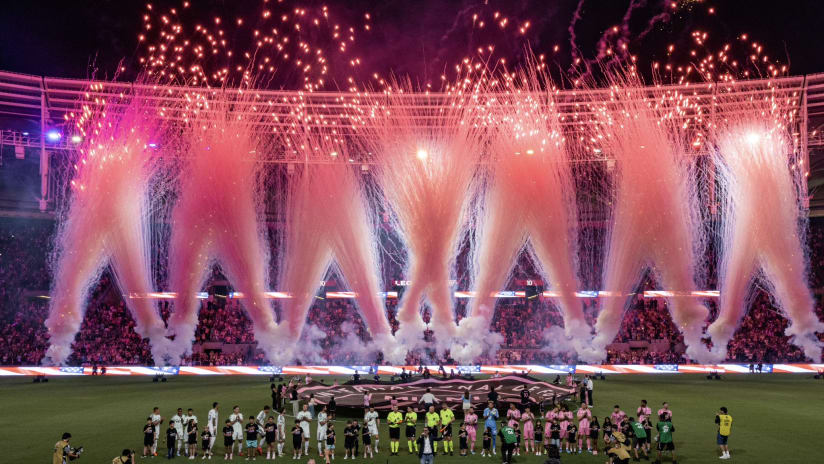 Fireworks display during stadium opening ceremony with players lined up on the field