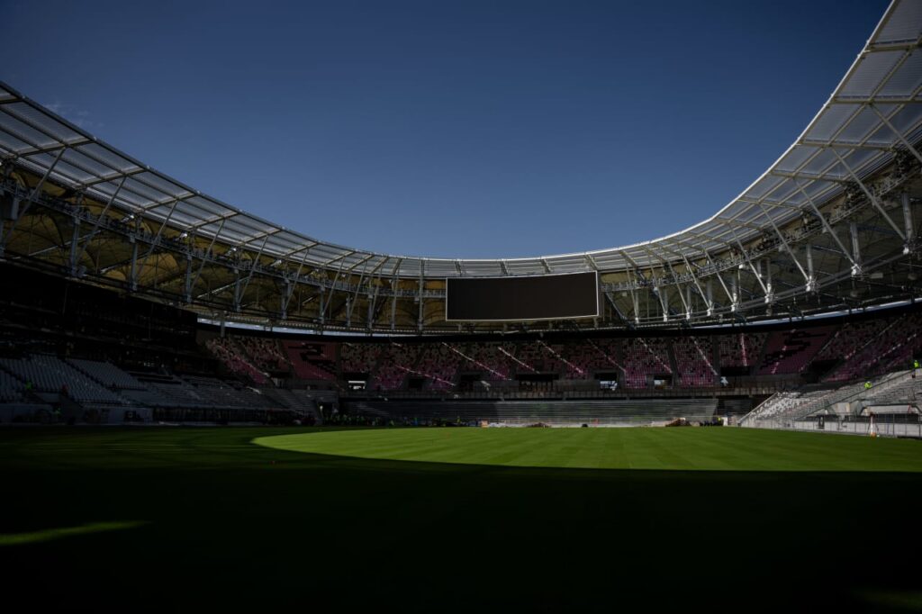 Empty stadium interior with field and seating under daylight