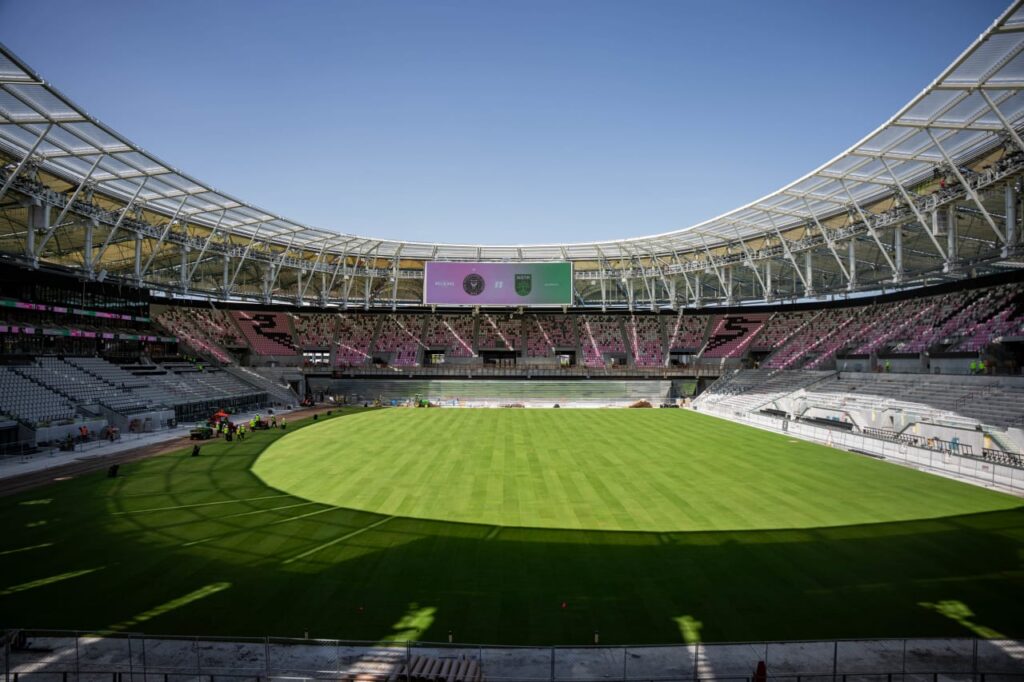 Stadium interior with field partially covered in shadow during construction