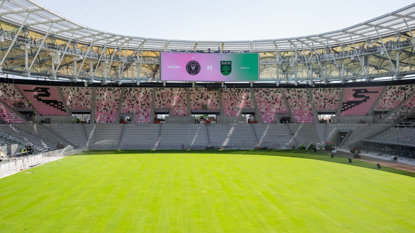 Interior view of stadium with scoreboard displaying match teams above field