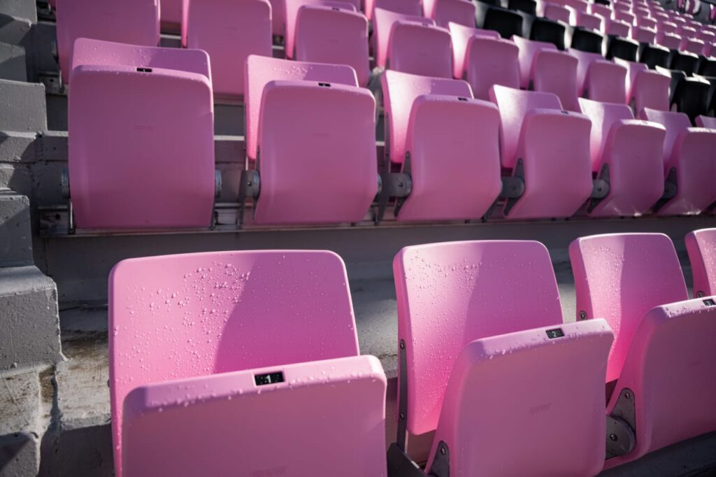 Close-up of pink stadium seats with water droplets