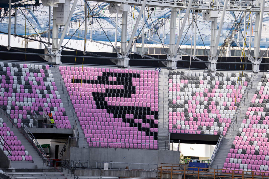 Stadium seating arranged in pink, black, and white forming a logo pattern