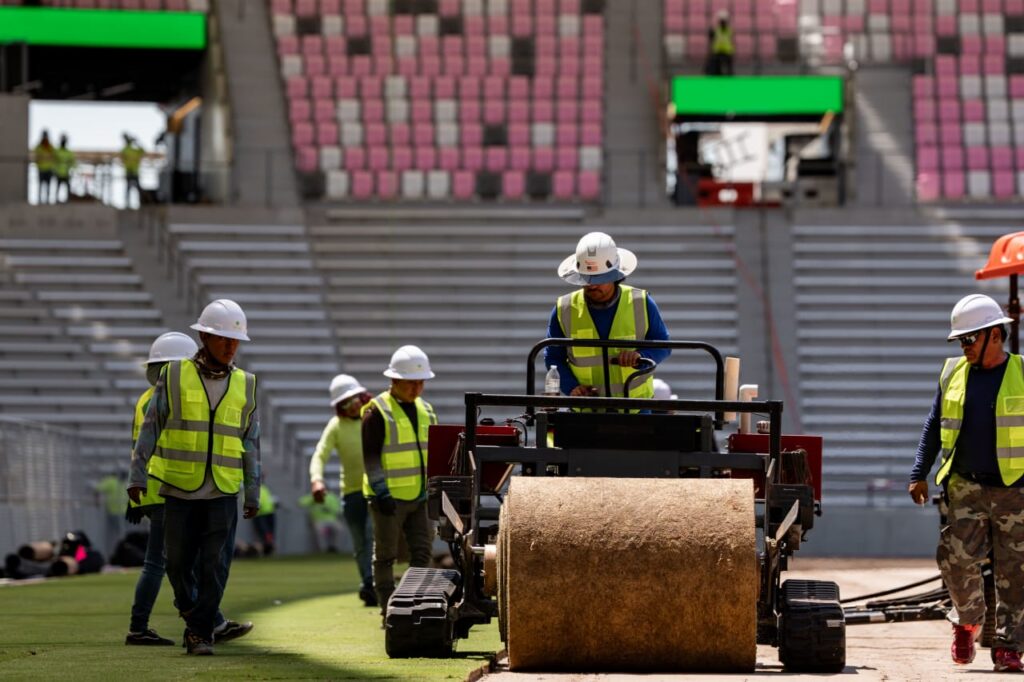 Construction workers installing turf on stadium field