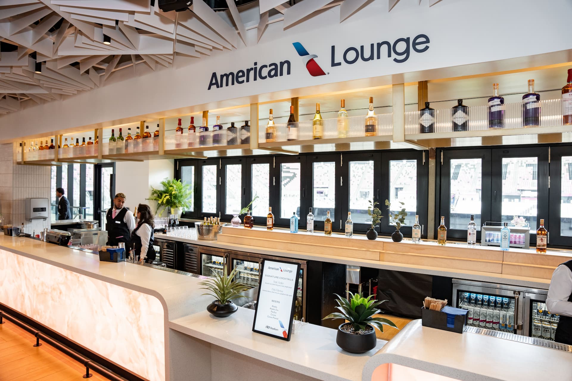American Airlines Lounge bar at NU Stadium featuring a modern counter, premium spirits, and bartenders.